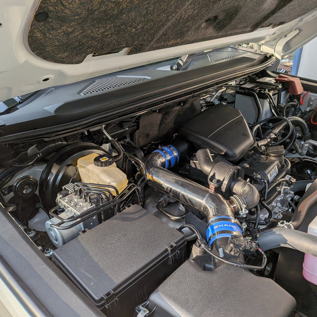EXART Toyota Land Cruiser 250 air-cleaner-side Air Intake Stabilizer, alternate engine-bay angle. Sound Generator version shown; throttle-side product sold separately.